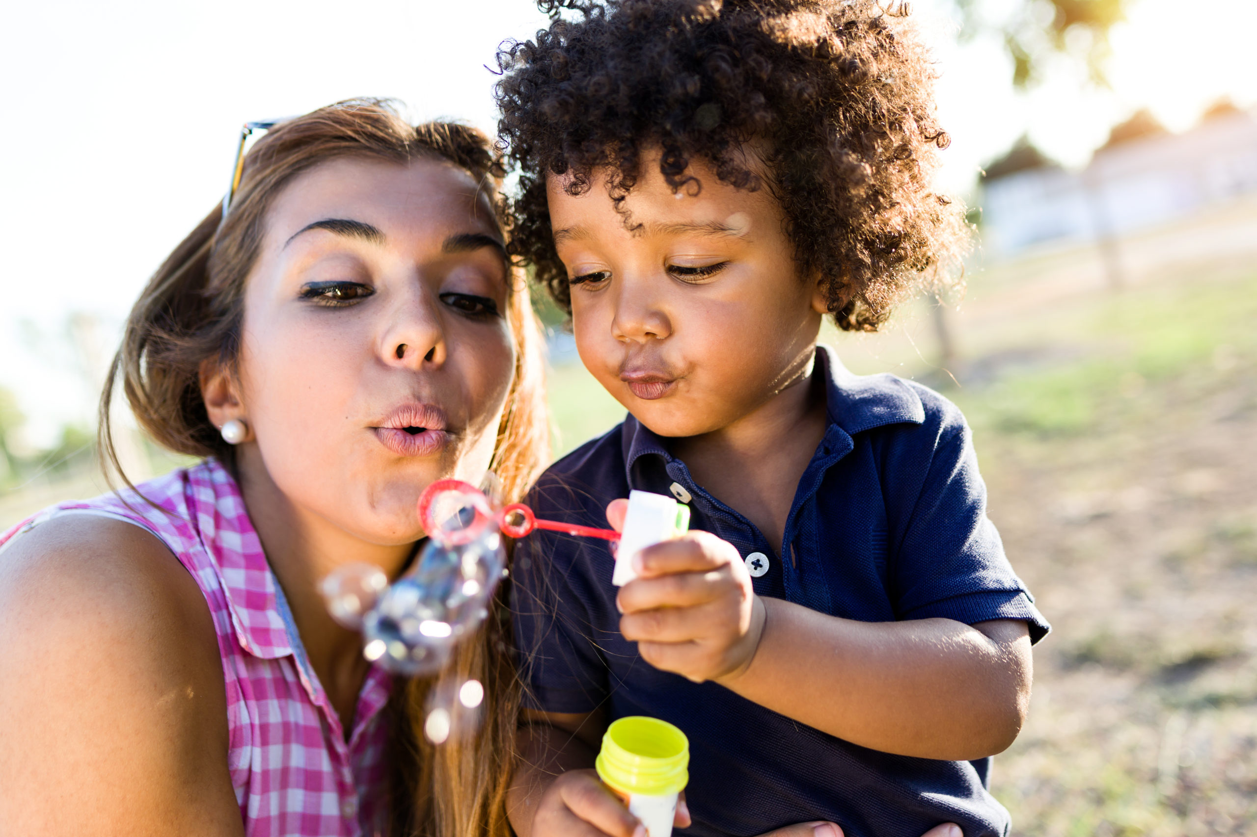 Beautiful young mother with her son blowing soap bubbles in the